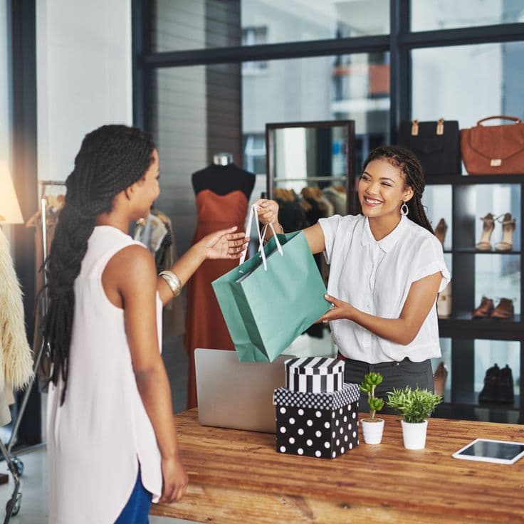 A seller handing a shopping bag to a happy customer
